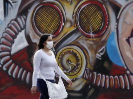 En Colombia la pandemia Exacerbó las Mipymes- Una mujer con tapabocas camina frente un grafiti en Bogotá (Colombia). EFE/Mauricio Dueñas Castañeda