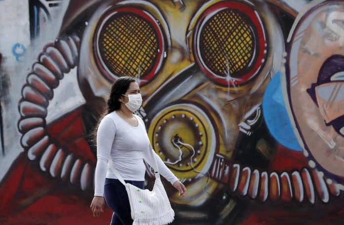 En Colombia la pandemia Exacerbó las Mipymes- Una mujer con tapabocas camina frente un grafiti en Bogotá (Colombia). EFE/Mauricio Dueñas Castañeda